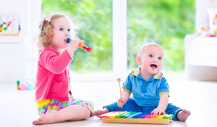 Two children happily playing with toys in a room, surrounded by newborn music toys, music stuffed animals, and classical music.
